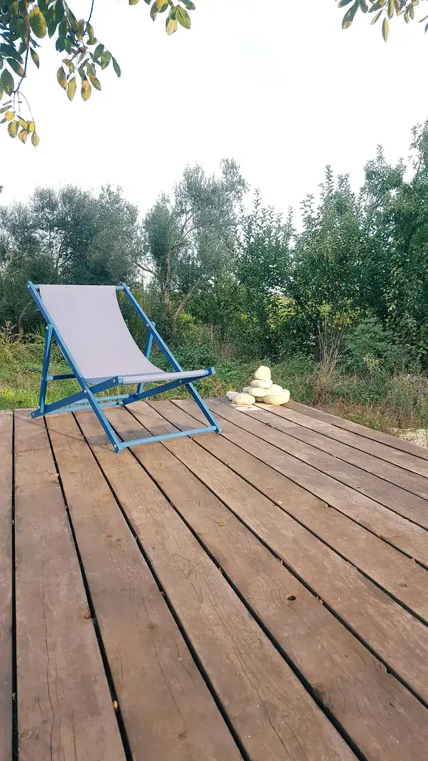 A striped deckchair on the wooden platform among the trees