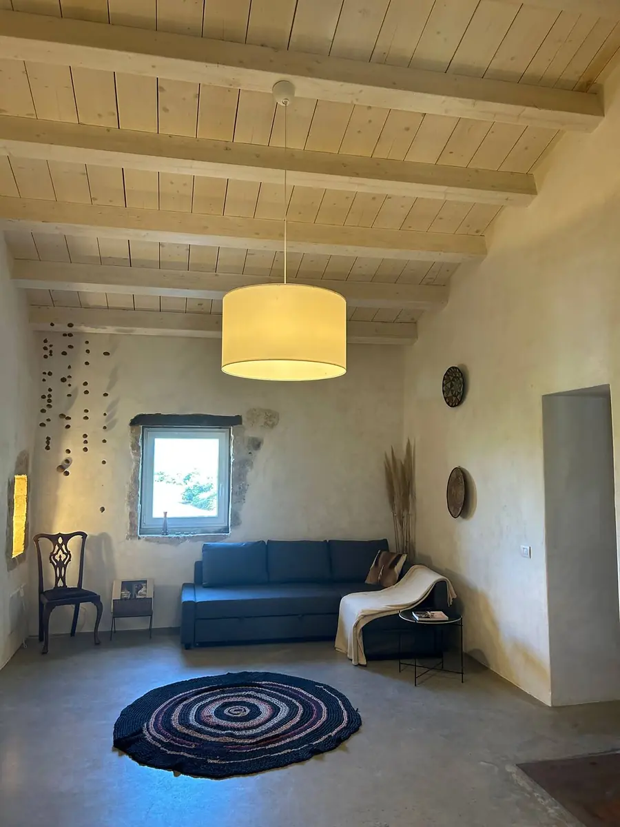 The private lounge: a deep blue sofa, a round woven rug and a pendant lamp under the beamed ceiling