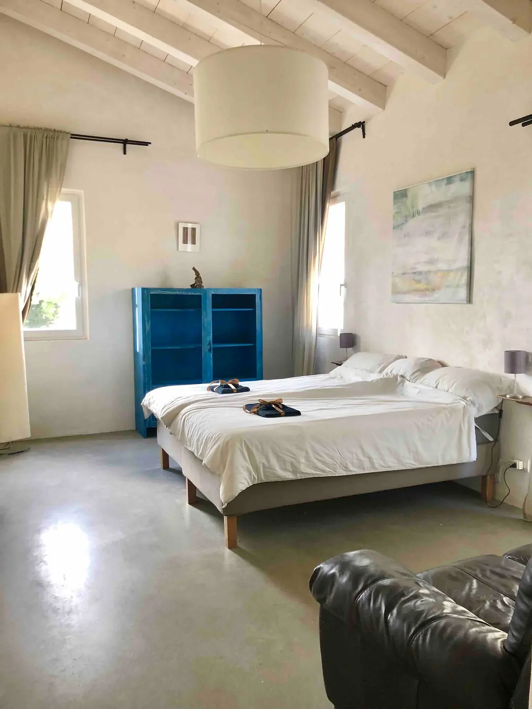Room 2: a king-size bed, a blue painted cabinet, a leather sofa and tall windows onto the trees
